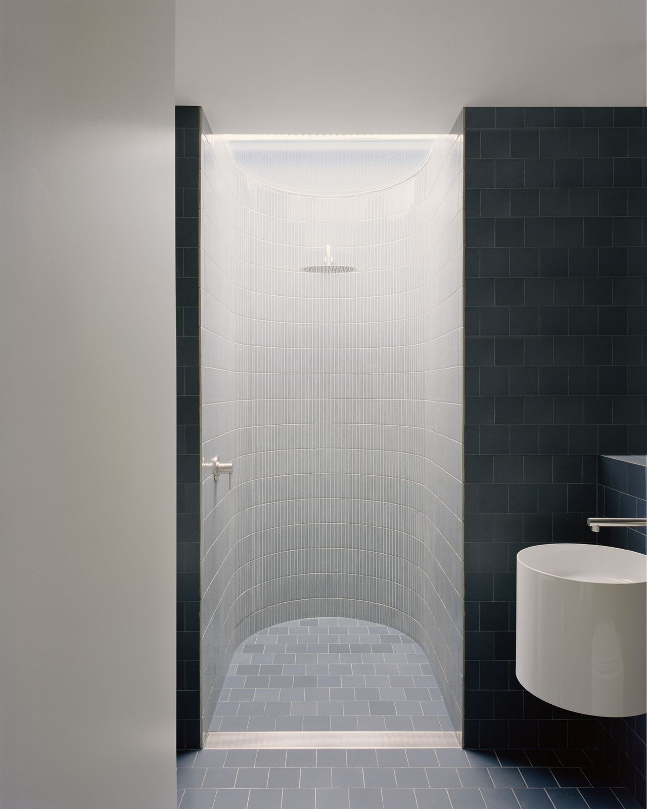 Alexandria House bathroom with shower niche, wall-hung basin, and blue and white tiles